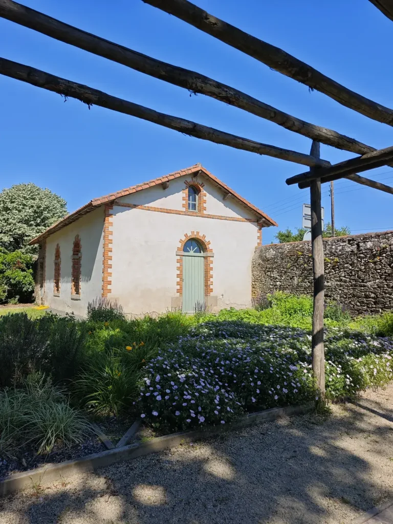 Une petite maison de pierre et de tuiles sous sa pergola, dans le vignoble